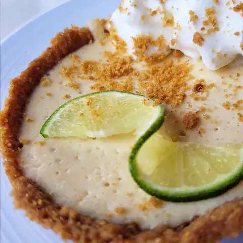 Slice of key lime pie topped with whipped cream and lime zest